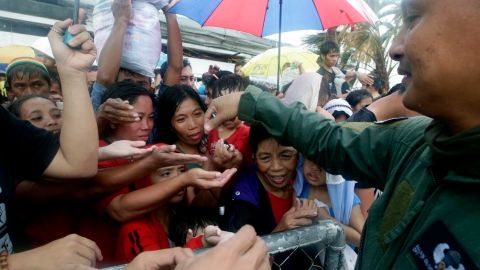 Mayormente mujeres, en Taclobán, hicieron lo imposible por alcanzar aunque fuera una de las golosinas que repartió uno de los militares.
