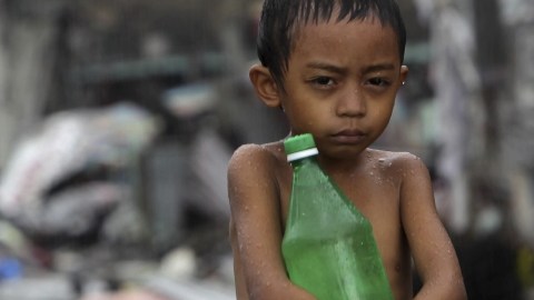 Un niño lleva una botella de agua bajo la lluvia en la ciudad de Tacloban.