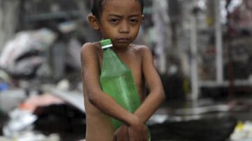 Un niño lleva una botella de agua bajo la lluvia en la ciudad de Tacloban.