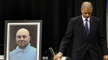 El fiscal general de Estados Unidos Eric Holder junto a un retrato del fallecido agente de la Administración de Seguridad en Transporte (TSA) Gerardo Hernández,en el homenaje realizado el 12 de noviembre de 2013, en Los Ángeles.