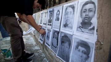 Un activista coloca retratos de desaparecidos en una de las paredes en la parte exterior del Congreso en Guatemala.