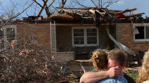 Ray Baughman abraza a su familia llorando momentos despues que vio  su casa destruida por uno de los tornados que afectó New Minden, en  Illinois. Muchos como él y su familia, deberán asistir a refugios donde permanecer por algún tiempo.