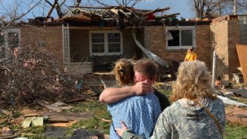 Ray Baughman abraza a su familia llorando momentos despues que vio  su casa destruida por uno de los tornados que afectó New Minden, en  Illinois. Muchos como él y su familia, deberán asistir a refugios donde permanecer por algún tiempo.