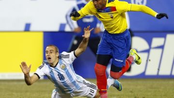 El argentino Rodrigo Palacio (18) cae mientras es marcado por el ecuatoriano Frickson Erazo (3), durante el amistoso que terminó sin anotaciones.