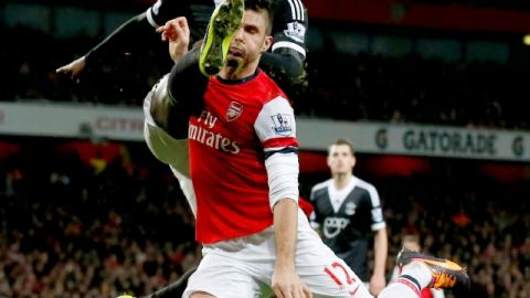 Olivier Giroud (12), autor de un doblete para Arsenal,  arriesga todo y  pelea el balón con   Victor Wanyama, en el Estadio Emirates.