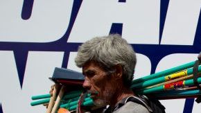 Un vendedor ambulante pasa junto a uncartel promoviendo el candidato presidencial del Partido Nacional, Juan Orlando Hernández, en Tegucigalpa, Honduras,