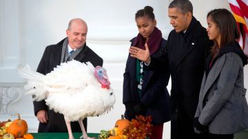 El presidente Barack Obama, junto a sus hijas Malia (der.), y Sasha (izq.), perdona al pavo “Popcorn”, durante la tradicional ceremonia en la Casa Blanca.