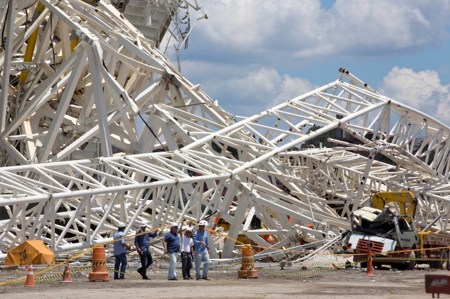 Oficiales inspeccionan los daños causados por la caída de una grúa en la Arena Corinthians, escenario del partido inaugural del Mundial de Brasil 2014.