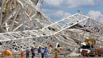 Oficiales inspeccionan los daños causados por la caída de una grúa en la Arena Corinthians, escenario del partido inaugural del Mundial de Brasil 2014.