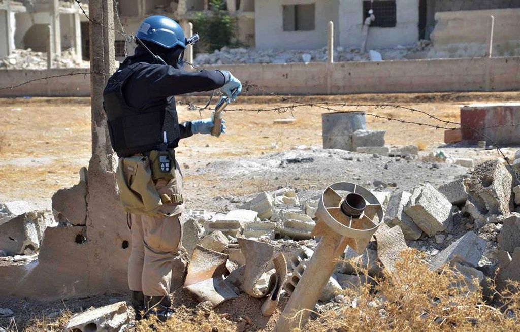 Miembros del grupo investigativo de las Naciones Unidas toman muestras de arena cerca de una zona impactada por misiles en Damasco.