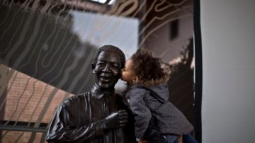 Una niña sudafricana es alzada por su madre para que  bese  una estatua del expresidente Nelson Mandela, en el Centro Nelson Mandela de la Memoria en Johannesburgo, Sudáfrica.