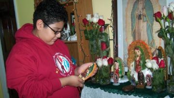 Angelito  junto al colorido altar a la Virgen de Guadalupe que levantó en su casa.