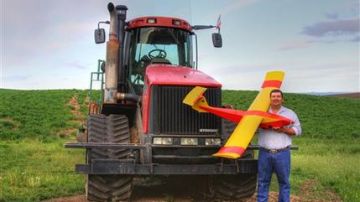 Imagen de mayo de 2013 que muestra al agricultor Robert Blair frente a su tractor sosteniendo una nave teledirigida que construyó, equipada con cuatro cámaras para vigilar su sembradíos.