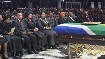 El presidente de Sudáfrica, Jacob Zuma (2L), la ex esposa de Nelson Mandela, Winnie Mandela Madikizela (L), y la viuda de Nelson Mandela, Graça Machel (3L), se sientan frente al ataúd del ex presidente sudafricano Nelson Mandela durante su ceremonia fúnebre en Qunu,