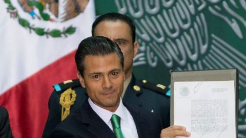 El presidente de México, Enrique Peña Nieto muestra los documentos que firmó que promulgan las reforma energética en el Palacio Nacional en la Ciudad de México, el viernes, 20 de diciembre 2013.