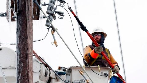Trabajadores tratan de restablecer el servicio, luego que el hielo y la nieve derribaron postes y cables de la red de electricidad.