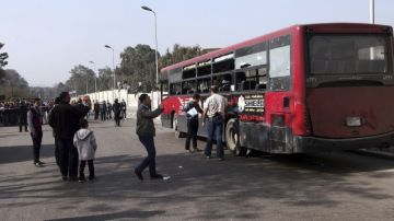 Oficiales de las Fuerzas de Seguridad inspeccionan un autobús, destruido en un atentado en el barrio de Ciudad Naser, en El Cairo  que dejó cinco heridos.