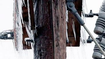 Trabajadores tratan de restablecer el servicio, luego que el hielo y la nieve derribaron postes y cables de la red de electricidad.