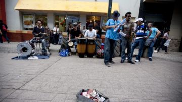 Un grupo de jóvenes músicos tocando en una plaza por dinero en Tegucigalpa. A la derecha, un paralítico pidiendo limosnas en una calle de Tegucigalpa.