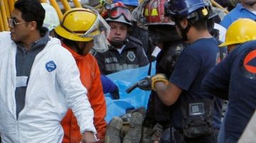 Socorristas trasladan a un trabajador de la construcción que falleció por el colapso de un edificio en Ciudad de México.