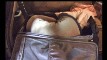 En la imagen suministrada por las autoridades se ve el cuerpo doblado de la mujer -con abrigo crema- dentro de la maleta.