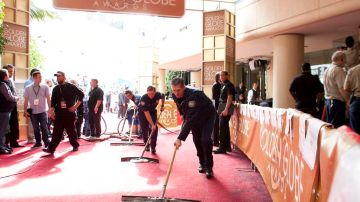 Empleados del Beverly Hilton Hotel limpian la alfombra roja después de que se inundara esta mañana.