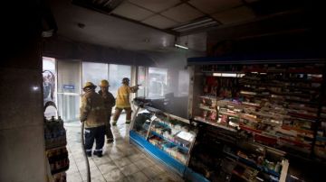 Bomberos realizan labores en una farmacia quemada en Apatzingán.