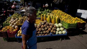 Una mujer camina frente a un puesto de ventas de verduras  en el mercado Israel Lewites, en Managua, Nicaragua, mientras se discute el salario minímo.