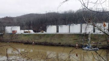 Trabajadores (i) inspeccionan una zona fuera de un muro de contención de los tanques de Freedom Industries desde donde se derramaron sustancias tóxicas en el río Elk, en Charleston, West Virginia.