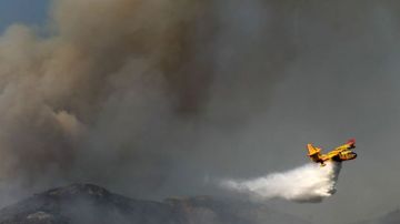 En esta foto del jueves, 16 de enero, se ve un avión de extinción de incendios lanzando agua en las colinas de Glendora, abrumadas por las llamas.