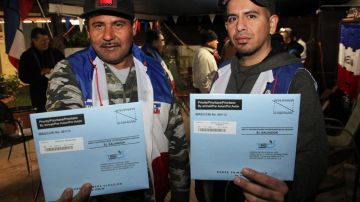Los salvadoreños José Rodríguez (izq.) y Francisco Sánchez muestran los sobres preparados con sus papeletas de votación a las elecciones presidenciales de su país.