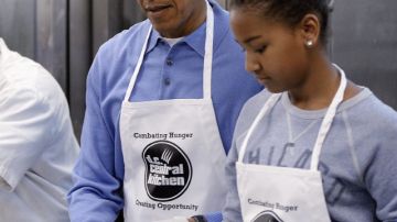 El presidente Barack Obama (2d), y su hija Sasha (d) participan en un proyecto de servicios comunitarios en Washington DC.
