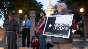 Mary Berwick, de Austin, Texas, der., un mimebro para la Abolición de la Pena de Muerte sostiene un cartel mientras el Padre John Calgaro,  de la Iglesia católica Cristo Rey (Izq.) ora por Edgar Tamayo.