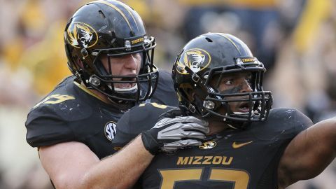 El jugador de fútbol americano de la Universidad de Mossouri Michael Sam (der.) es felicitado por su compañero Matt Hoch durante un partido entre Missouri y el Sudeste de Louisiana.
