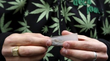 En esta foto se observa a un joven, con una camisa alusiva a la planta, liando un cigarillo de esa yerba dentro del marco de  la Marcha Mundial de la Marihuana.