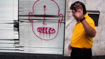 Un hombre pasa frente una sucursal bancaria con diferentes mensajes pintados durante la protesta  en Caracas.
