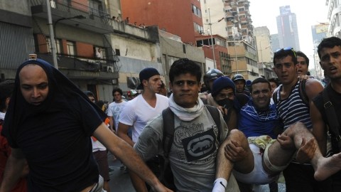 Un hombre herido es cargado por sus compañeros durante la violenta protesta en Caracas.