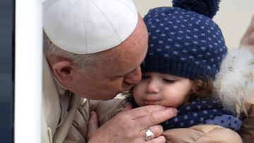 El papa Francisco besa a una niña mientras saluda a los fieles congregados en la plaza de San Pedro del Vaticano para recibir la bedición papal.