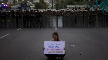 Una mujer participa en una manifestación de la oposición venezolana frente a una barrera policial.