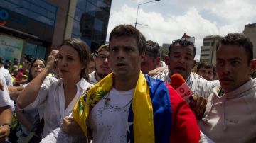 Leopoldo López arropado con la bandera venezolana mientras oficiales lo dirigen a un cuartel.