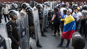 Miembros de la policía venezolana tratan de frenar una marcha de los estudiantes ayer en las calles de Caracas.
