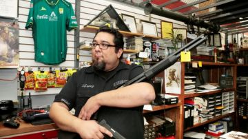 Alejandro López, de Western Firearms, muestra una  Mossberg y una pistola semiautomática.