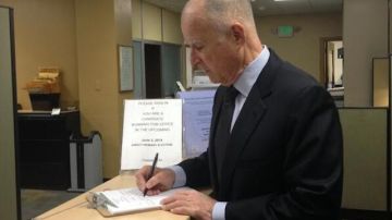 Jerry Brown firmando los papeles para postularse nuevamente como candidato a gobernador de California en las próximas elecciones.