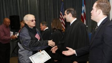 El secretario puertorriqueño de Estado, David Bernier (der.), entrega certificados a nuevos ciudadanos americanos en San Juan.