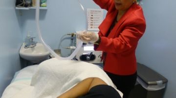 La naturópata Hilda Pichardo muestra a una paciente el equipo usado para la limpieza del colon.