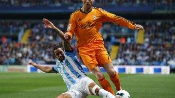 Cristiano Ronaldo aguanta la barrida del jugador del Málaga,  Alberto Angeleri (izq.) durante el juego de ayer en La Rosaleda.