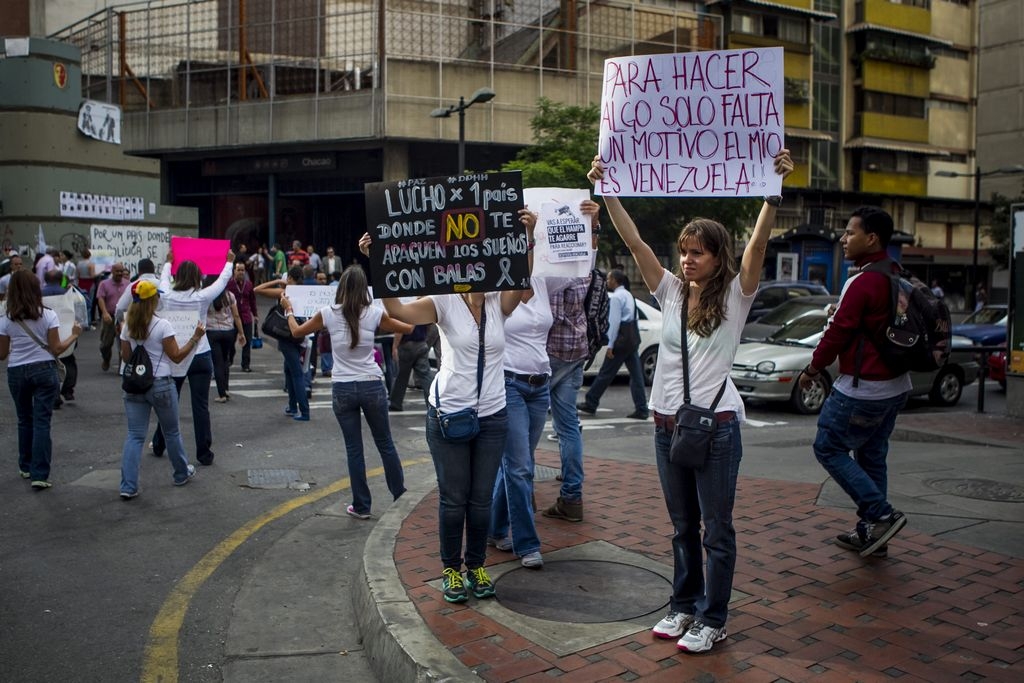 Un grupo de opositores al Gobierno muestra unos carteles con mensajes de protesta en la avenida Francisco de Miranda en Caracas.