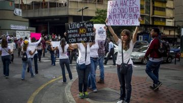 Un grupo de opositores al Gobierno muestra unos carteles con mensajes de protesta en la avenida Francisco de Miranda en Caracas.