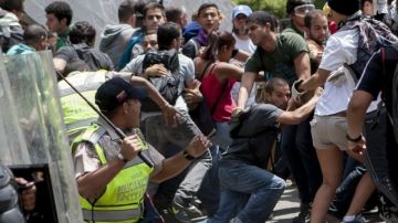 Manifestantes opositores se enfrentan a miembros de la Policía Nacional Bolivariana, tras una concentración convocada por las organizaciones opositoras estudiantiles en Caracas, ayer.