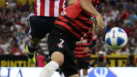 Óscar Razo, del Atlas, disputa el balón con Jorge Enríquez,  de Chivas, ante 48,538 aficionados en la cancha del Estadio Jalisco.